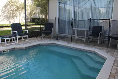 a swimming pool with chairs and a table in a house at Veteran Owned 3bdr/3 bath Townhouse w/WiFi 3mi to Disney - Fall/Winter Specials in Kissimmee