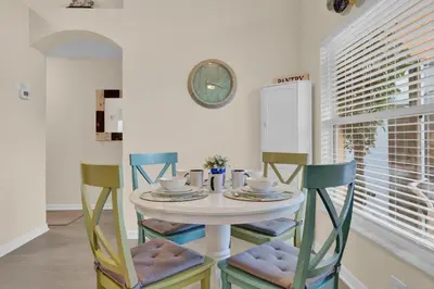 a dining room with a table with chairs and a clock at Disney Getaway Villa in Kissimmee