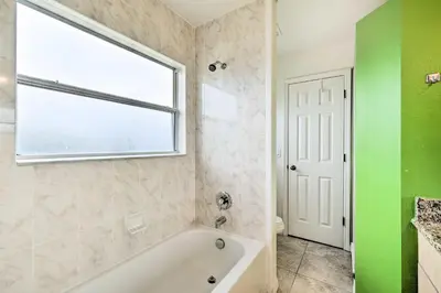 a bathroom with a white tub and a window at Dog-Friendly Kissimmee Home with Lanai and Pool! in Kissimmee
