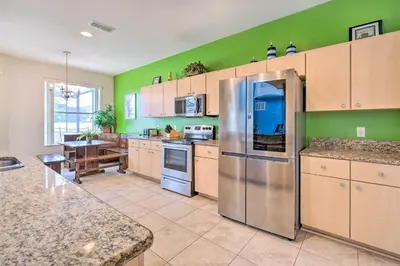 a kitchen with green walls and a stainless steel refrigerator at Dog-Friendly Kissimmee Home with Lanai and Pool! in Kissimmee