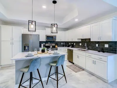 a kitchen with white cabinets and blue bar stools at Homely Lakeview 3BR Condo with Waterpark in Kissimmee