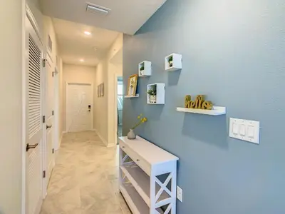 a hallway with a blue wall with a white desk at Gorgeous 2BR lakeview Condo with Waterpark in Kissimmee