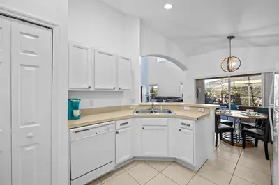 a white kitchen with a sink and a table at Near Disney, Recently Renovated, Clubhouse in Kissimmee