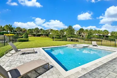 a swimming pool in a yard with two chairs at Vibrant Home Near Disney With Media Room, Themed Rooms, Game Room And Waterpark & Resort Access At Encore Resorts Reunion - 7450Mr in Kissimmee