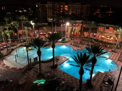 a large pool with palm trees in a city at night at Designer Corner Suite 3BR/2BA -Disney & Universal in Orlando