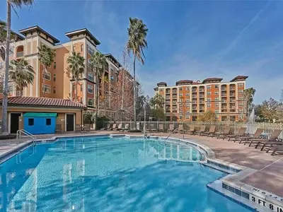 a large swimming pool with chairs and buildings at Designer Corner Suite 3BR/2BA -Disney & Universal in Orlando