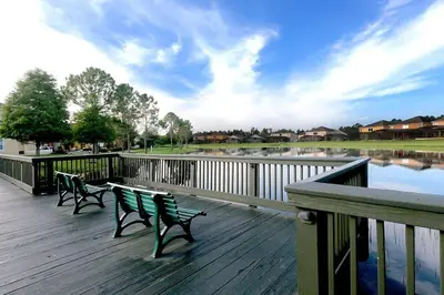 two benches on a boardwalk next to a body of water at Newly Renovated Stylish Villa with Star Wars Mickey and Safari Themed Rooms #3TV4706 in Kissimmee