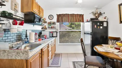 a kitchen with a black refrigerator and a table at La Maison de Lorbu - Apartment in Orlando