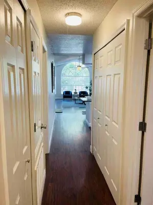 a hallway with two white doors and a living room at Luxury • Modern • CLOSE2DISNEY • 3bed • 2bath in Kissimmee