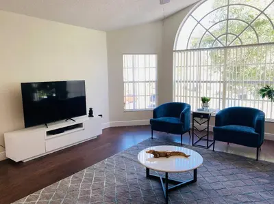 a living room with a tv and two chairs and a table at Luxury • Modern • CLOSE2DISNEY • 3bed • 2bath in Kissimmee
