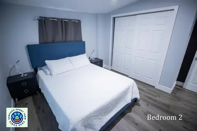 a bedroom with a white bed with a blue headboard and a door at The Contemporary in Sanford