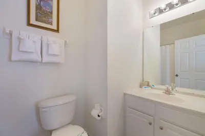 a bathroom with a toilet and a sink and a mirror at Windsor Dream - 6 bedroom resort pool home in Orlando