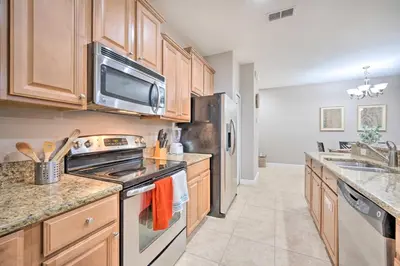 a kitchen with wooden cabinets and a stove top oven at Private Pool and Lanai Resort Townhome in Kissimmee in Kissimmee