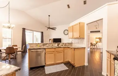 a kitchen with wooden cabinets and a living room at East Orlando Getaway - 3BR/2BTH - *Pool *Parking in Orlando