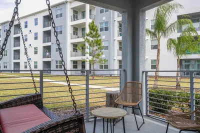 a porch with chairs and a table and a swing at Resort Condo Near Disney FREE Waterpark 3120 in Kissimmee