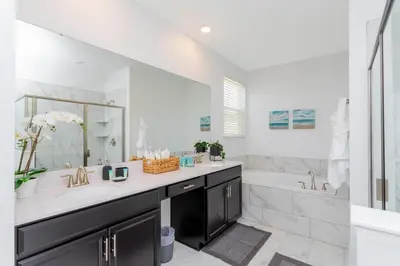a bathroom with a sink and a tub and a mirror at Resort-Style Private Pool & Spa Modern 2920 in Kissimmee