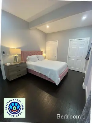 a bedroom with a bed with a nightstand and a bed sidx sidx sidx sidx at The Front Porch in Sanford