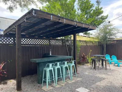 a wooden pergola with stools and a table and chairs at The Jazz Loft in Sanford