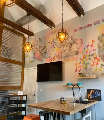 a kitchen with a table and a tv on the wall at The Jazz Loft in Sanford