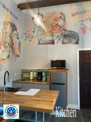 a kitchen with a wall with a painting of a man at The Jazz Loft in Sanford