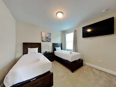 a bedroom with two beds and a flat screen tv at 561 - 8BD Villa - Private PoolSpa by Disney in Orlando