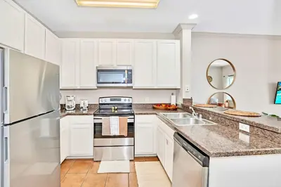 a kitchen with white cabinets and stainless steel appliances at Stylish 3BR Suite with Swimming Pool - Near Disney in Orlando