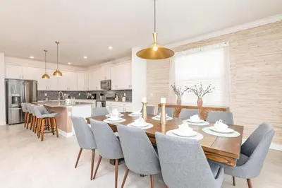 a kitchen and dining room with a wooden table and chairs at Luxury home, private pool, themed bedrooms, prime location in Kissimmee