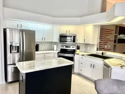 a kitchen with white cabinets and stainless steel appliances at Dreamy Family Pool House in Clermont