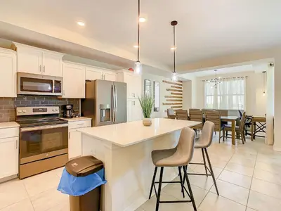 a kitchen and dining room with a counter and chairs at Wonderful 2BR Condo with 2 Clubhouses in Kissimmee