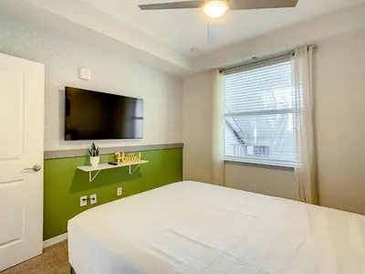 a bedroom with a white bed and a flat screen tv at Wonderful 2BR Condo with 2 Clubhouses in Kissimmee