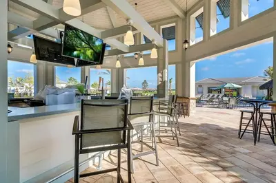 a patio with chairs and a bar with a flat screen tv at Resort Life at Storey Lake by Shine Villas, #702 apts in Kissimmee