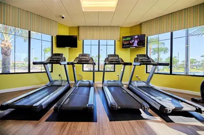 a gym with three treadles in a room with windows at Sweet Suite Sleeps 6 Storey Lake by Shine Villas apts in Kissimmee