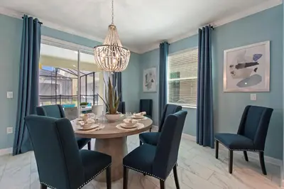 a dining room with a table and chairs and a chandelier at Stars Align Storey Lake by Shine Villas villa in Kissimmee