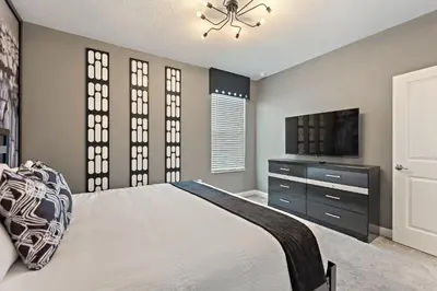 a bedroom with a bed and a tv and windows at Stars Align Storey Lake by Shine Villas villa in Kissimmee