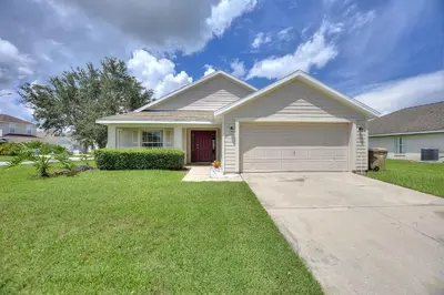 a house with a dog sitting in the front yard at Gilded Parasol by Shine Villas Remington Golf #410 home in Kissimmee