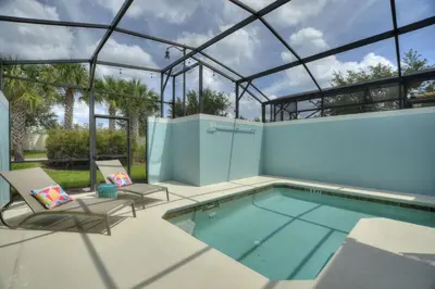a swimming pool with two chairs and a glass house at Haven Station at Storey Lake by Shine Villas townhouse in Kissimmee