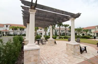 a patio with a wooden pergola with tables and benches at Happy Haven at Storey Lake Resort by Shine Villas condo in Kissimmee