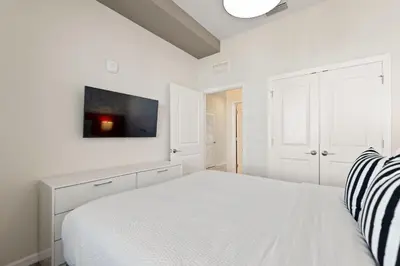 a white bedroom with a bed and a tv on the wall at Duck House at Storey Lake by Shine Villas #992 apts in Kissimmee