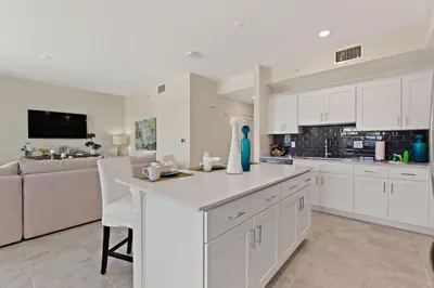 a kitchen with white cabinets and a living room at Tranquility at Storey Lake by Shine Villas #828 apts in Kissimmee