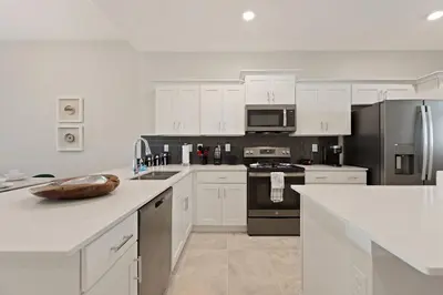 a kitchen with white cabinets and stainless steel appliances at Edgewater Escape at Storey Lake by Shine Villas apts in Kissimmee