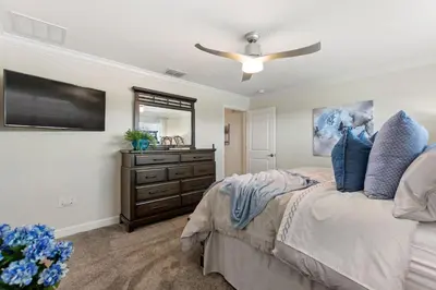 a bedroom with a bed with a ceiling fan and a dresser at Plush Pelican, at Storey Lake by Shine Villas #839 home in Kissimmee