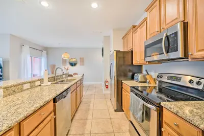 a kitchen with wooden cabinets and a stove top oven at 5 Mi to Disney Paradise Palms Retreat with Lanai in Kissimmee