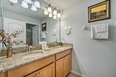 a bathroom with two sinks and a large mirror at 5 Mi to Disney Paradise Palms Retreat with Lanai in Kissimmee