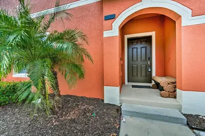 a palm tree in front of a building with a door at 5 Mi to Disney Paradise Palms Retreat with Lanai in Kissimmee