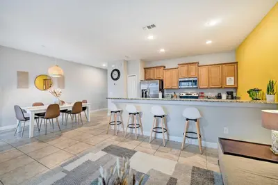 a kitchen and dining room with a table and stools at 5 Mi to Disney Paradise Palms Retreat with Lanai in Kissimmee