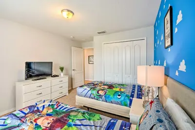 a bedroom with two beds and a flat screen tv at 5 Mi to Disney Paradise Palms Retreat with Lanai in Kissimmee