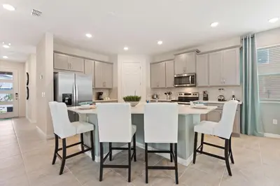 a kitchen with a large island with white chairs at Sea Shore at Solara Resort by Shine Villas #401 villa in Orlando