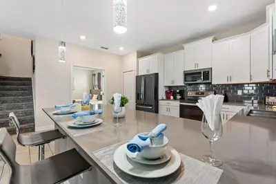 a kitchen with white cabinets and a table with dishes at Treat Retreat Storey Lake by Shine Villas #418 villa in Kissimmee