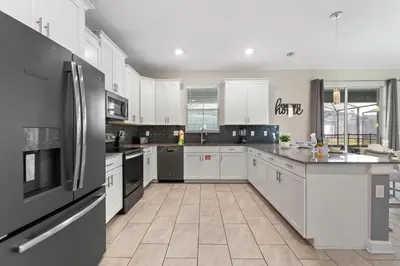 a large kitchen with white cabinets and black appliances at Treat Retreat Storey Lake by Shine Villas #418 villa in Kissimmee