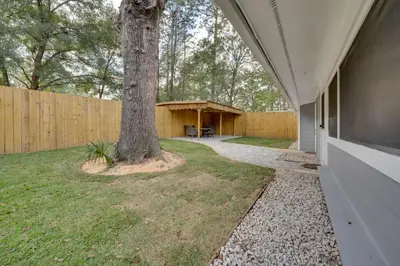 a house with a tree next to a fence at Apopka Home with Yard and Grill Near Wekiwa Springs! in Apopka
